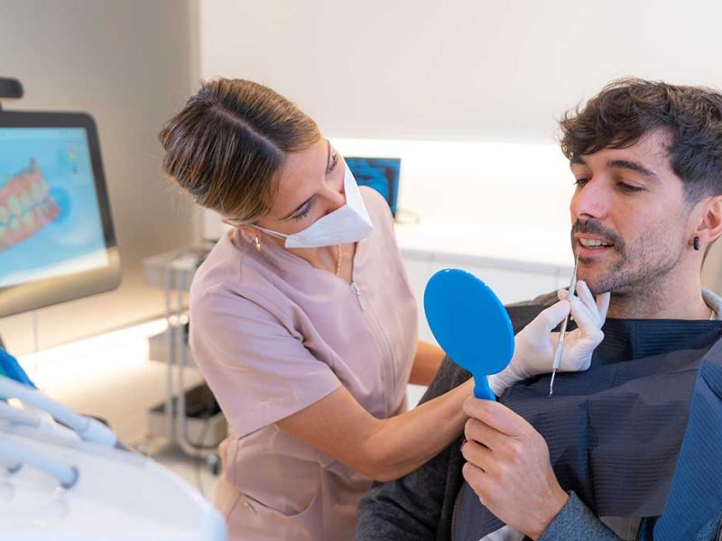 Patient using a mirror to look at the dental results in a dental clinic
